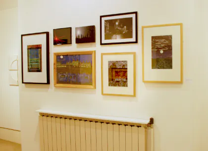 A group of pictures sit above a radiator in a white walled gallery