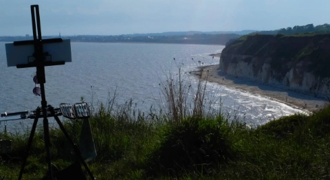 An illustration of an artist's easel set up on a high cliff overlooking a dramatic sea view with high-contrast lighting.